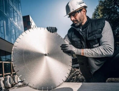 Ouvrier chantier qui tient un grand disque diamant entre ses mains